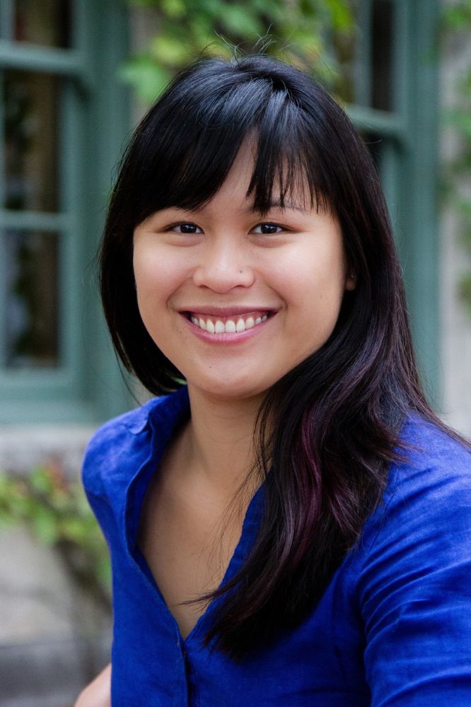 Headshot of a smiling woman with black hair past her shoulders in a blue blouse